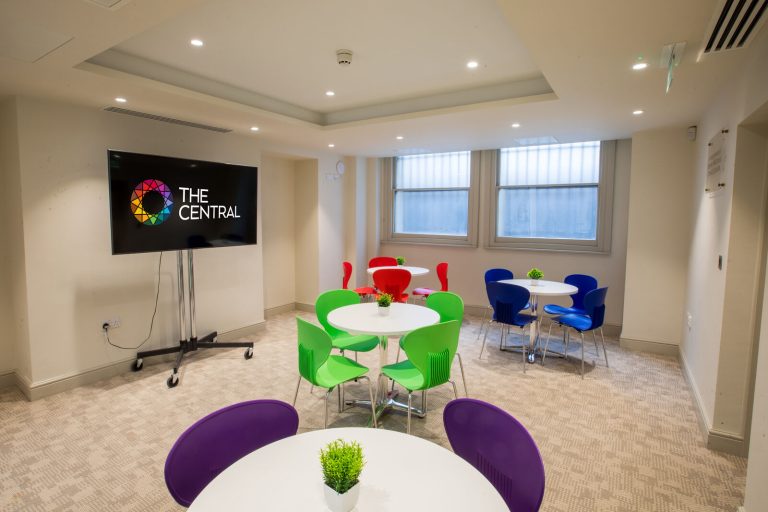 A conference room with small round tables with colourful chairs.