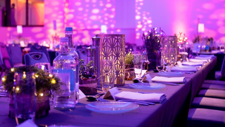 A table which has been dressed for an event with plates, glasses and candles.